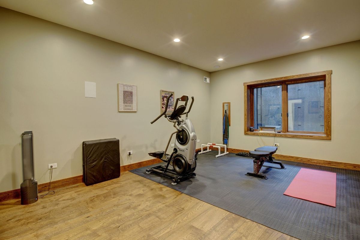 There is a gym in the basement with a elliptical machine and a yoga mat.