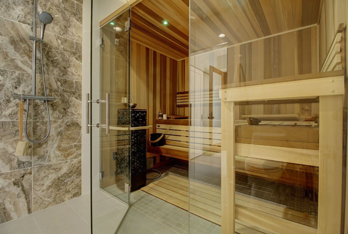A bathroom with a wooden sauna and a glass shower.