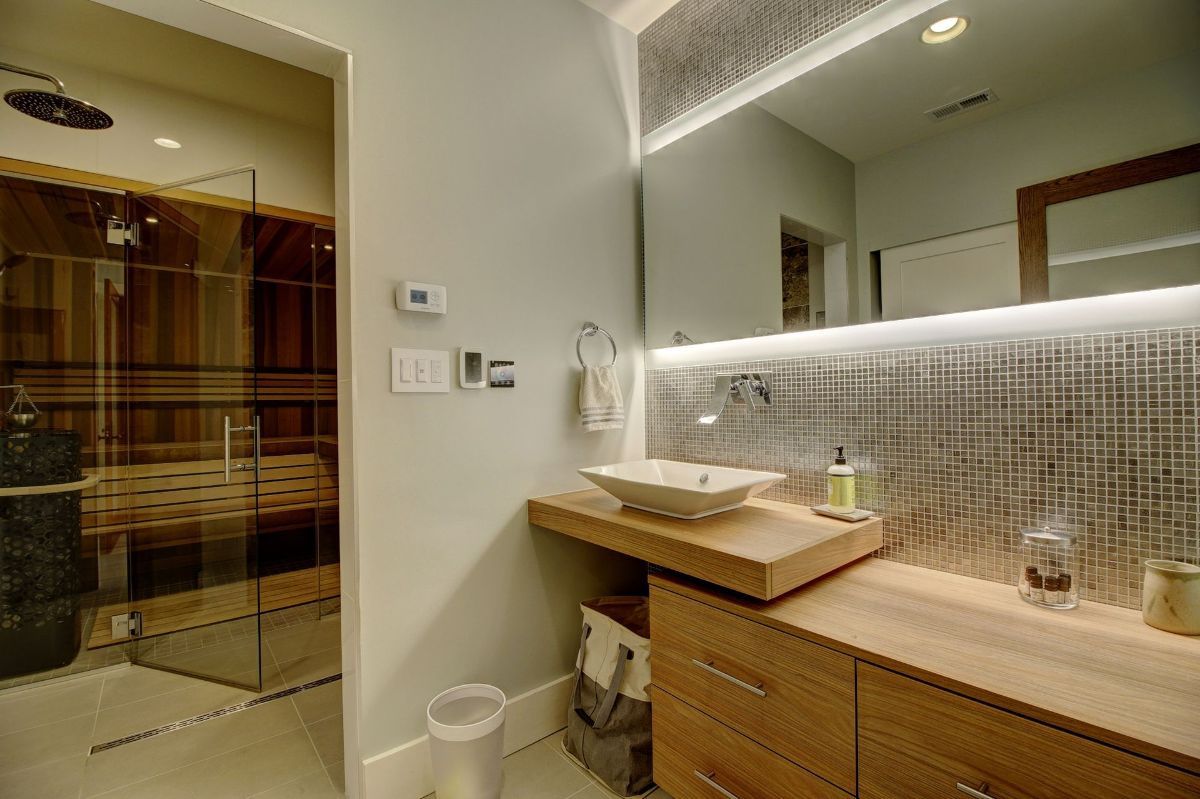 A bathroom with a sink , mirror and sauna.
