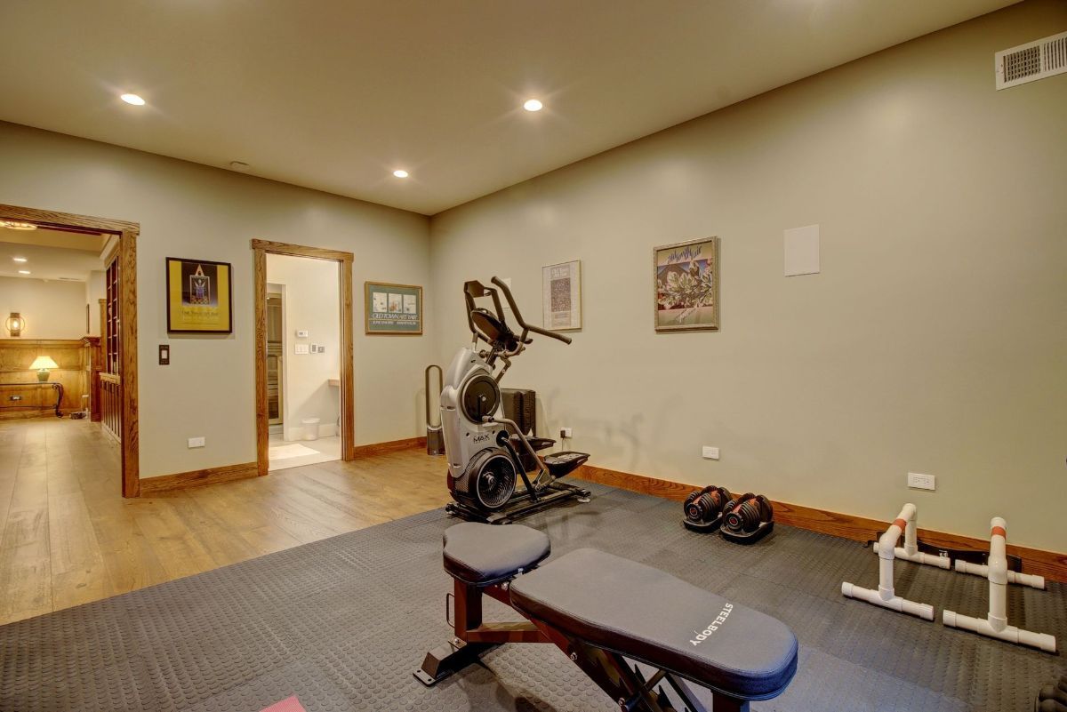 A home gym with a bench , exercise bike , and dumbbells.