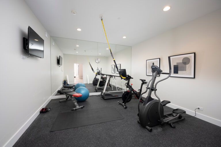 A gym with a lot of exercise equipment and a large mirror.