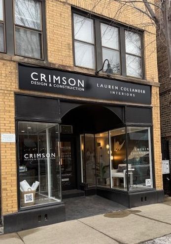 The front of a brick building with a black sign that says crimson design & construction.