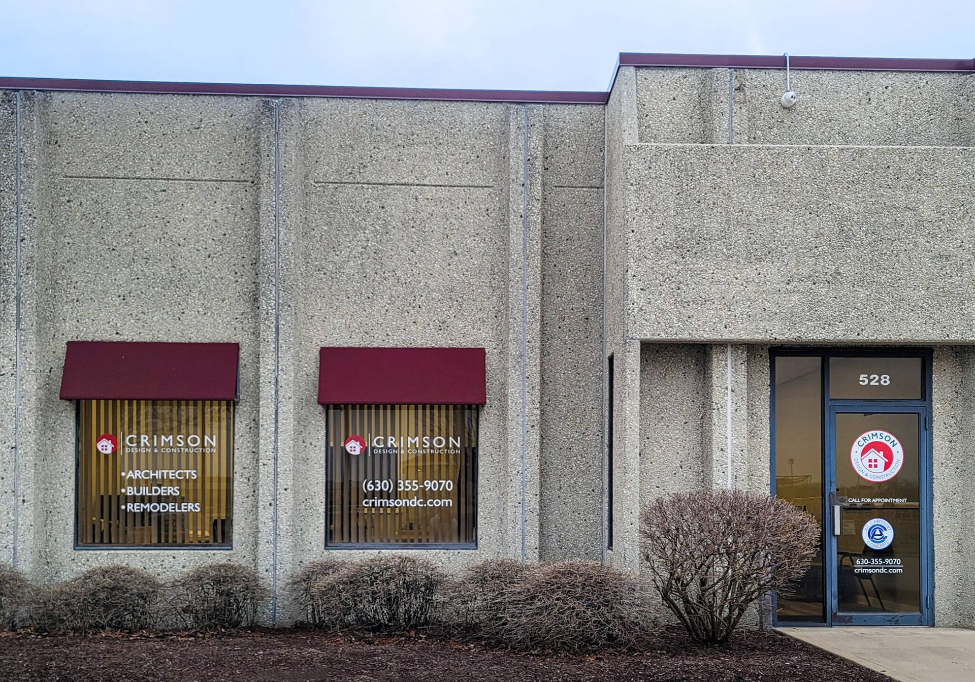A concrete building with a red awning on the windows