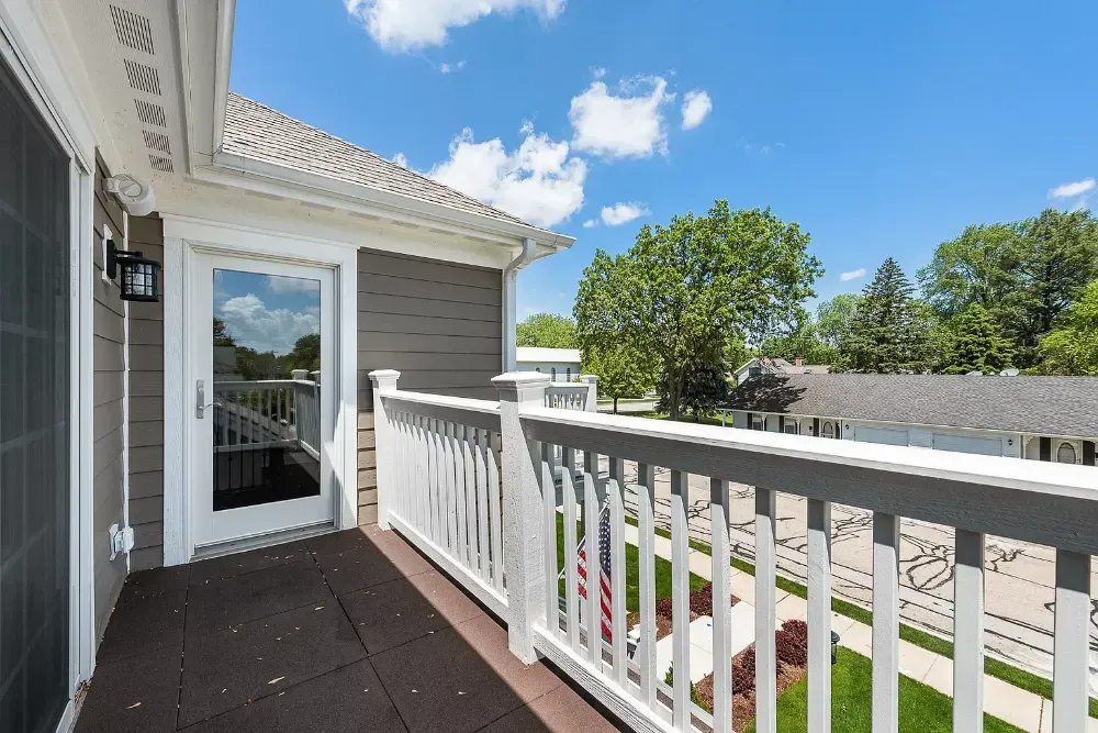 There is a balcony with a white railing and a sliding glass door.