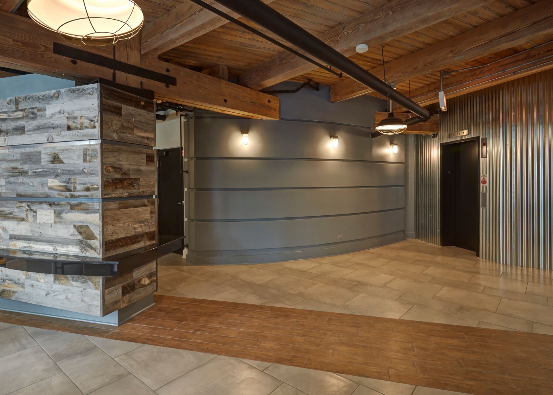 A large empty room with a wooden wall and a metal wall.