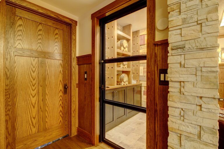 A hallway with wooden doors and a glass door leading to a kitchen.