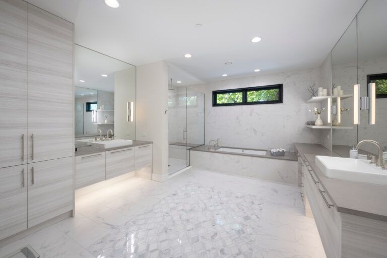 A bathroom with two sinks , a tub , and a large mirror.
