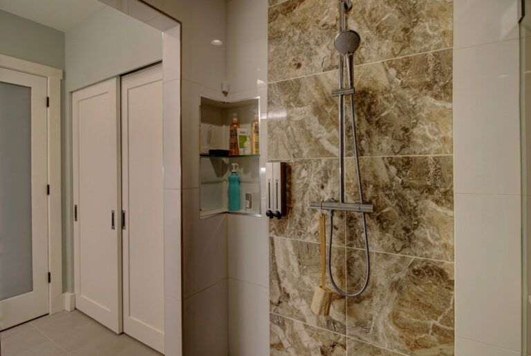 A bathroom with a walk in shower and a marble wall.
