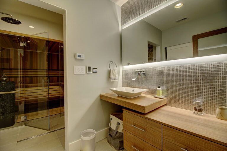 A bathroom with a sink , mirror and sauna.