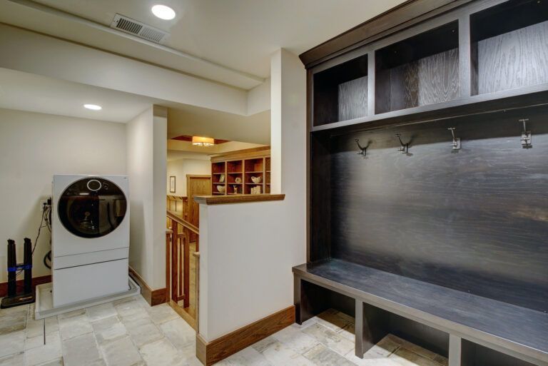 A laundry room with a washer and dryer and a bench.