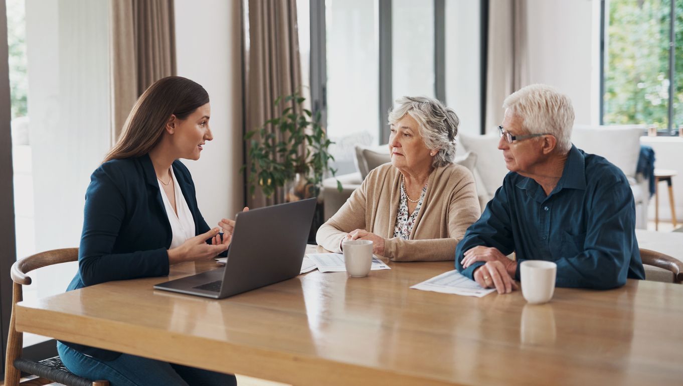 elderly couple meeting with a woman at a laptop