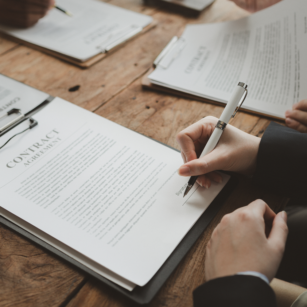 A person is signing a contract on a clipboard