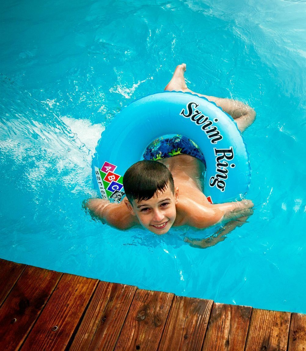 A young boy is swimming in a pool with a swim ring