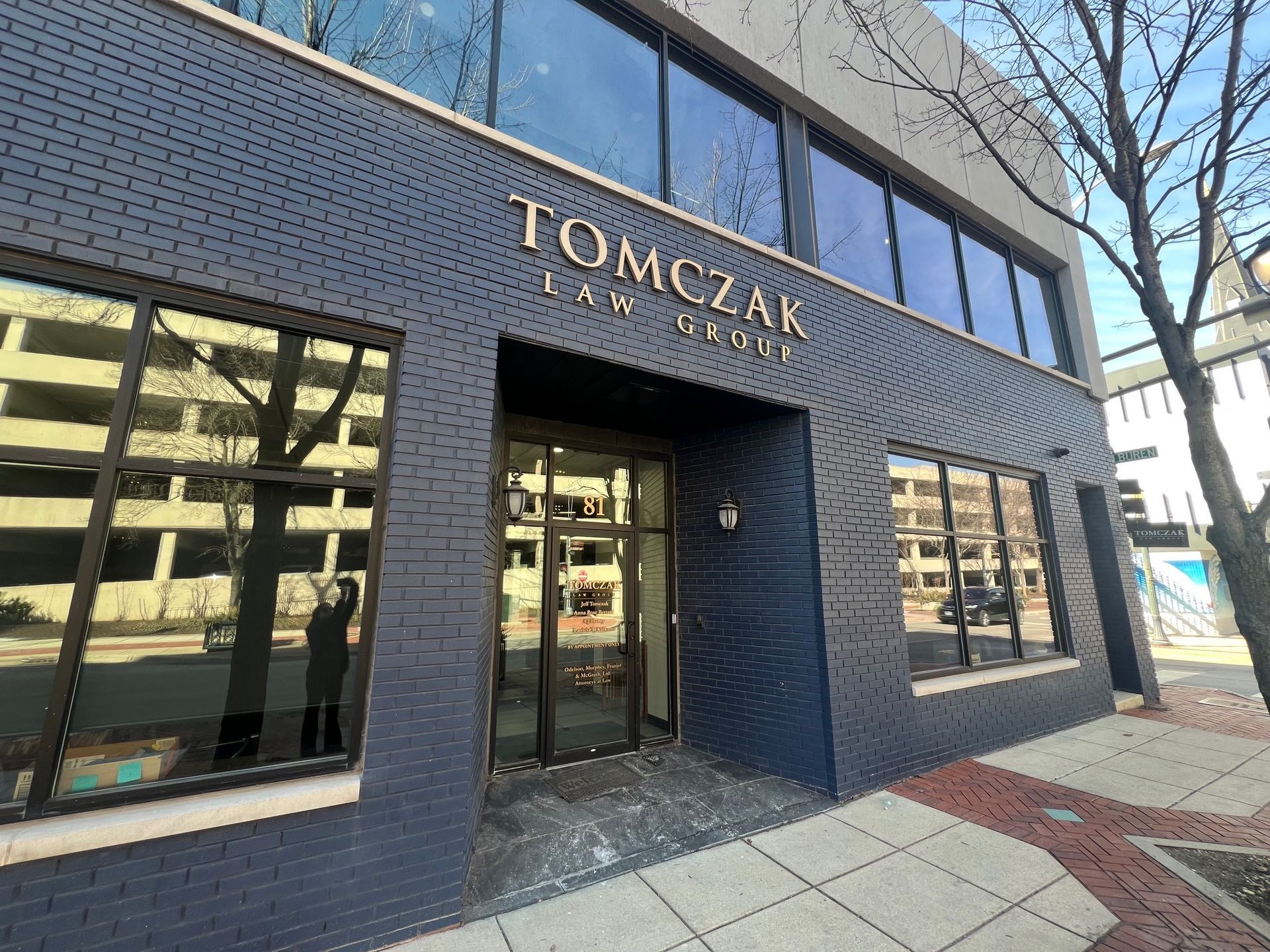 A tan two-story building with a white sign above the glass entrance doors reading 