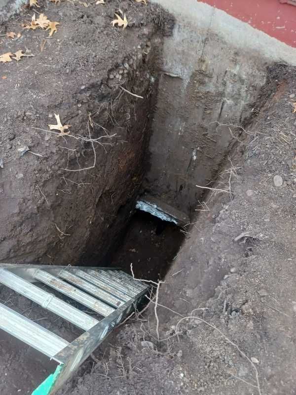 Hole leading to an exposed home foundation with a ladder