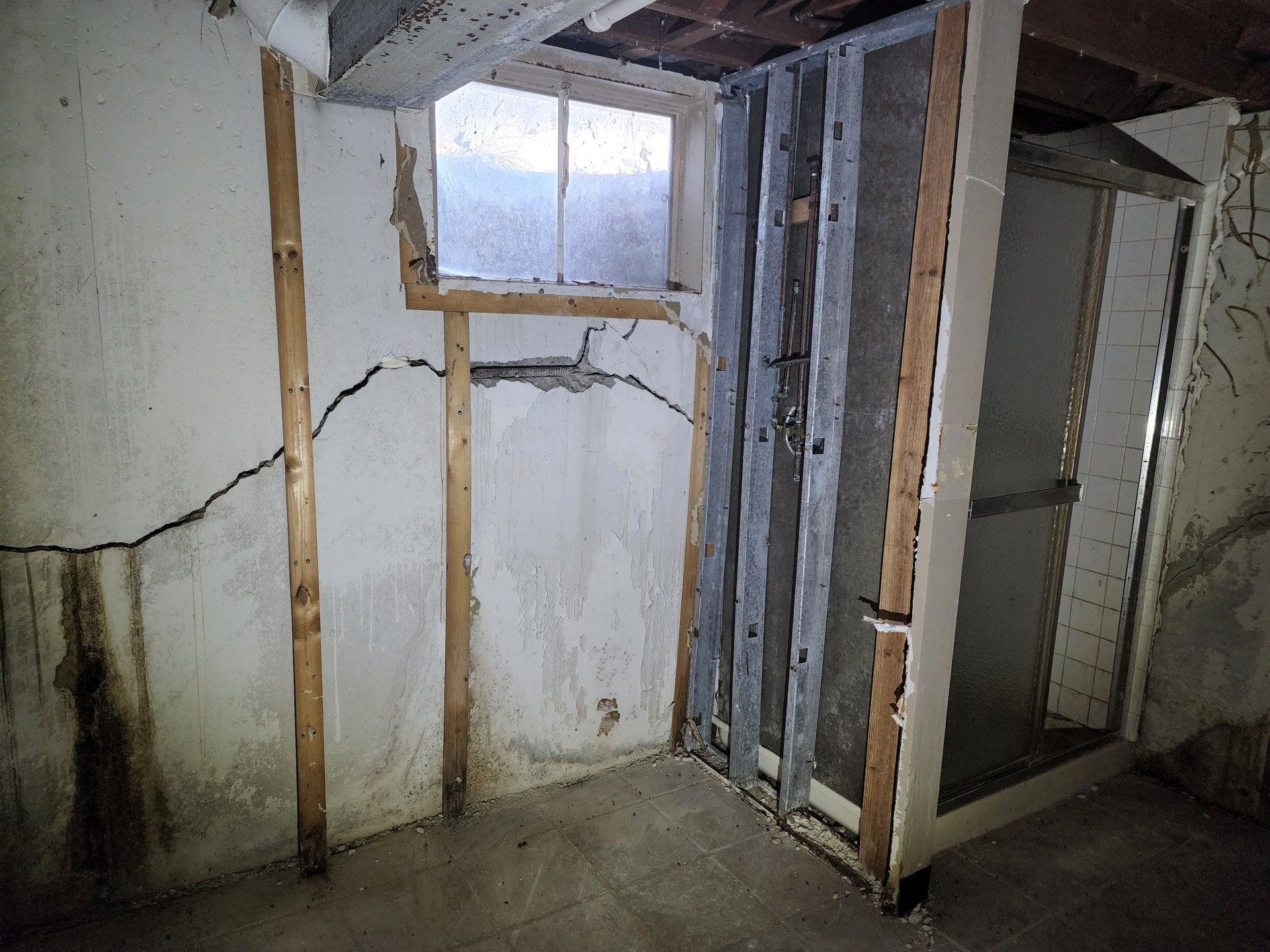 interior of a basement with a large horizontal crack in the concrete wall