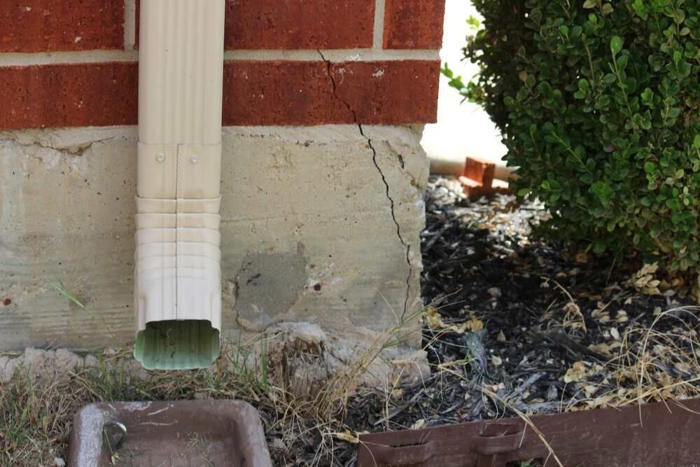 A crack in a foundation due to a misdirected gutter spout. 