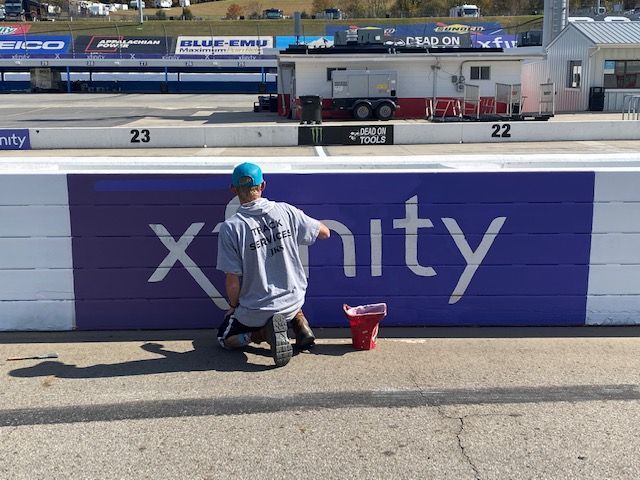 A man paints a sign that says xfinity on it