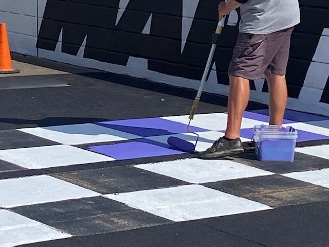 A man is painting a checkered floor with a roller
