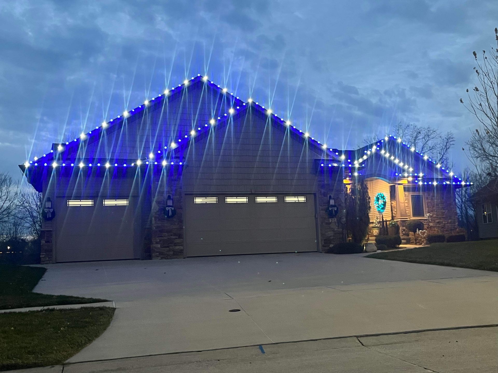 A house is decorated with blue and white christmas lights.