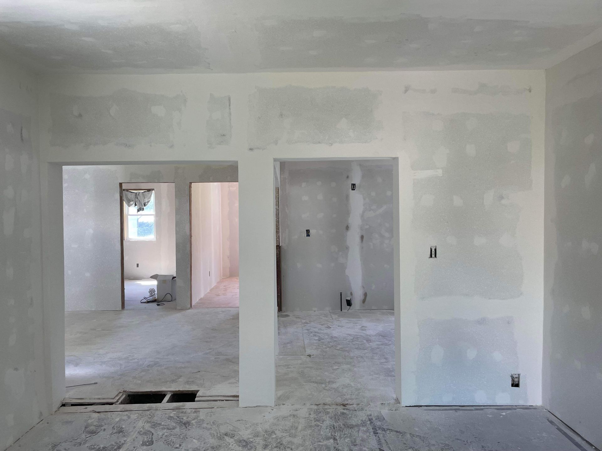 An empty room with drywall on the walls and a hole in the floor.