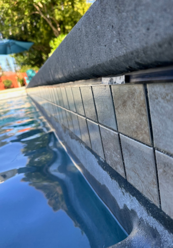 A close up of a tiled edge of a swimming pool.