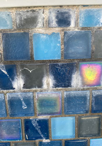 A close up of a wall with blue tiles on it.