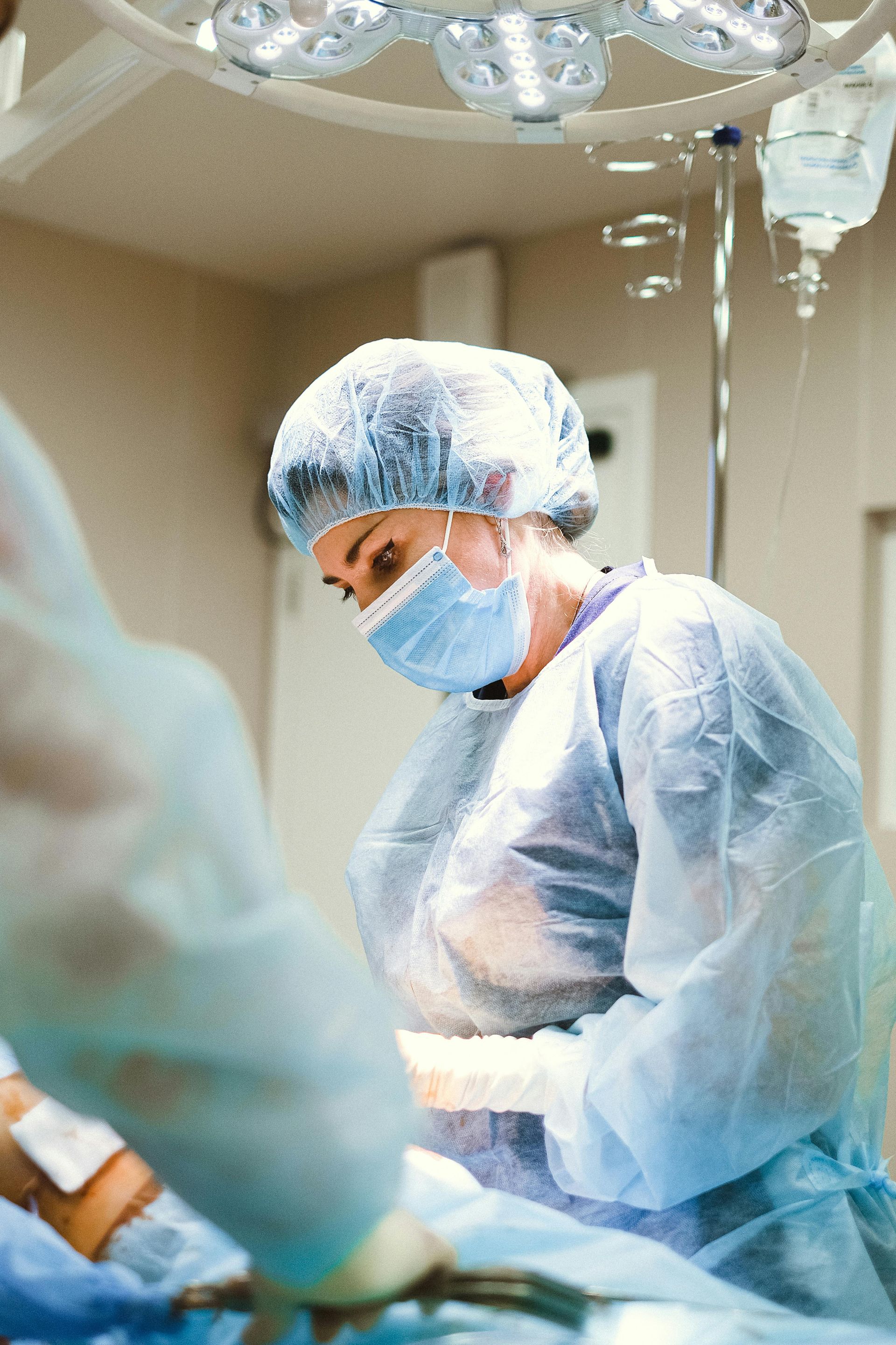Surgeon wearing protective gear in operating room, focused on a procedure.