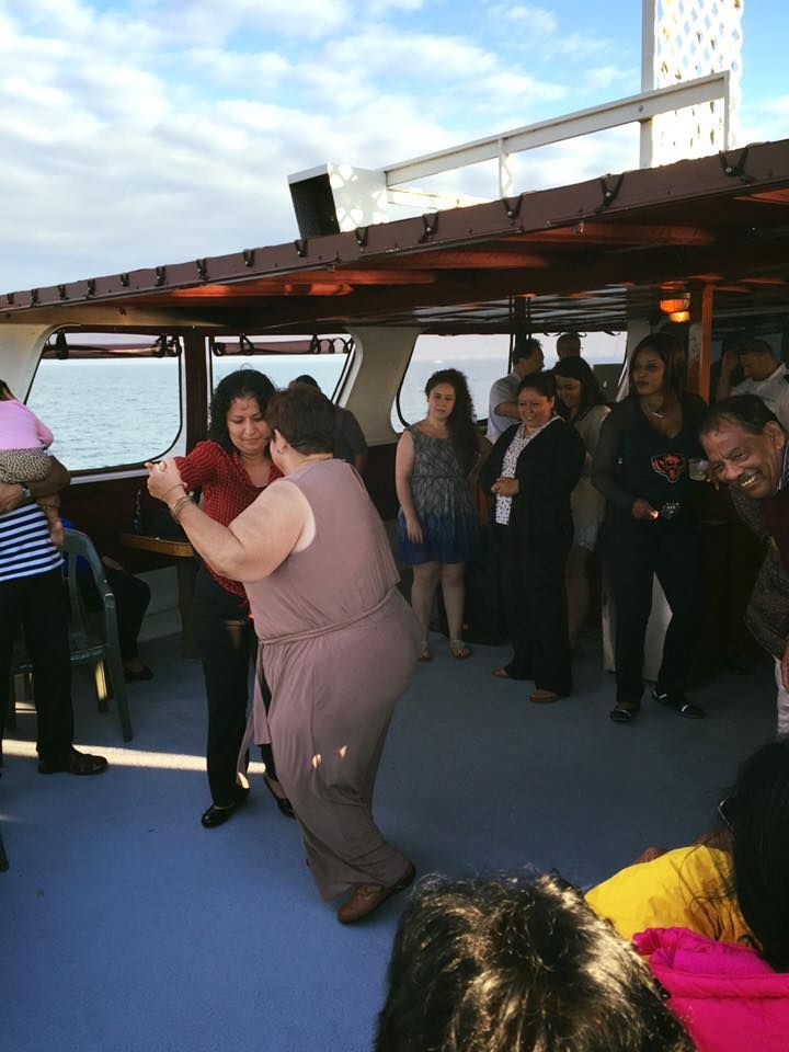 People dancing on an outdoor boat deck under a bright sky