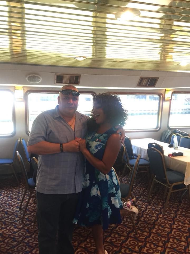 Couple posing together in a bright dining room aboard a ship, holding hands and smiling.