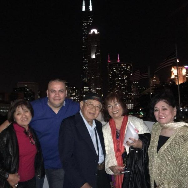 Five people posing at night with city skyscrapers and lights behind them