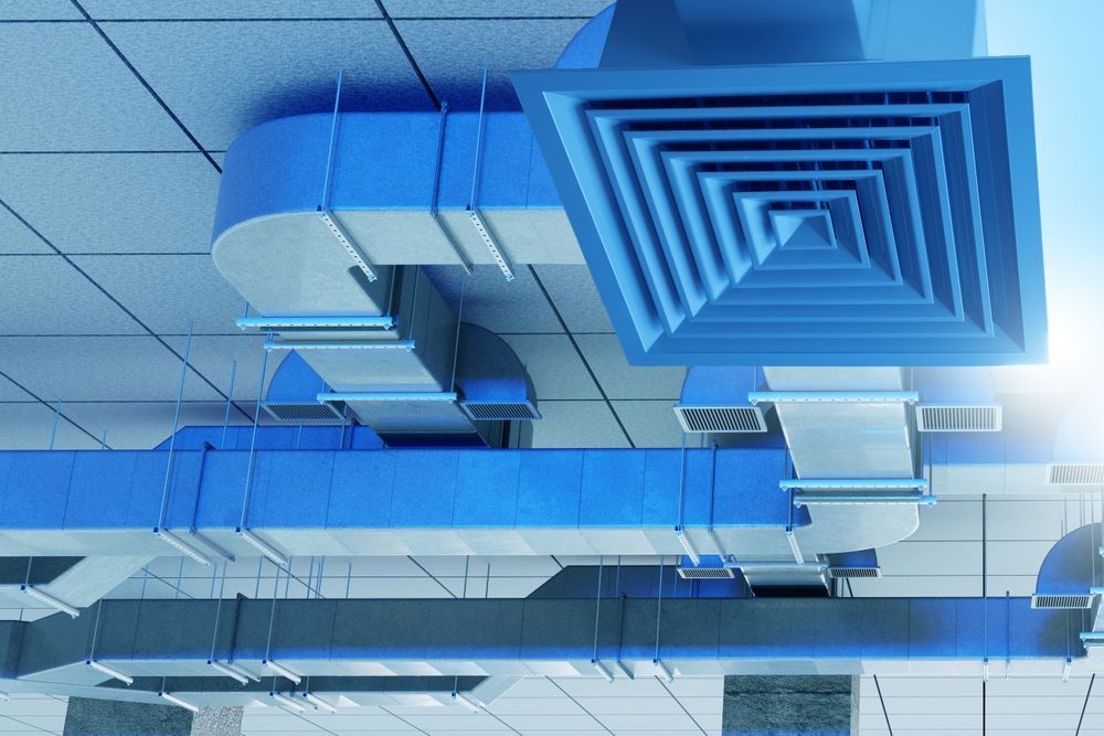 Blue industrial ventilation ducts and ceiling vents in a tiled interior ceiling.
