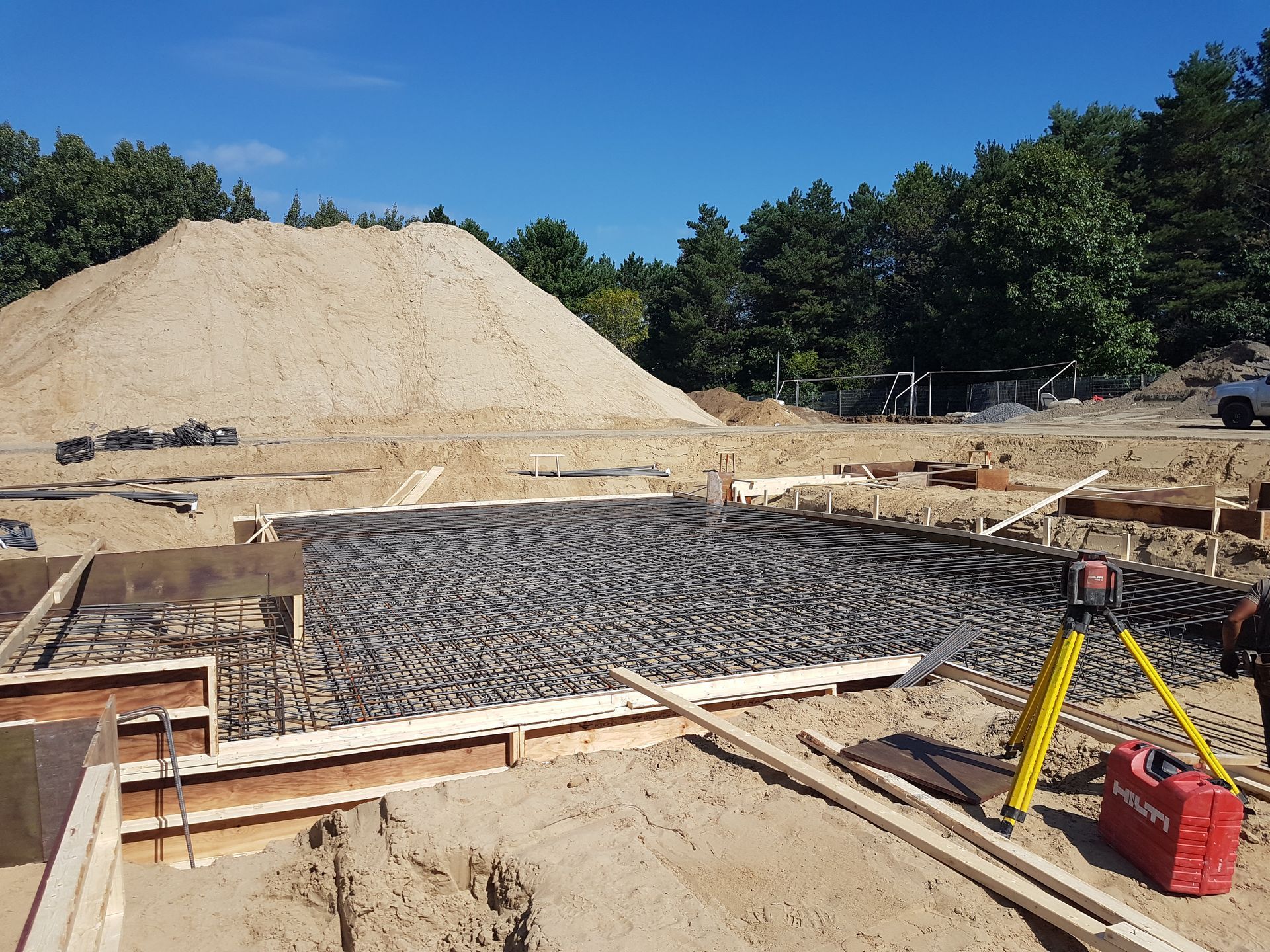 Un chantier de construction avec un gros tas de sable en arrière-plan
