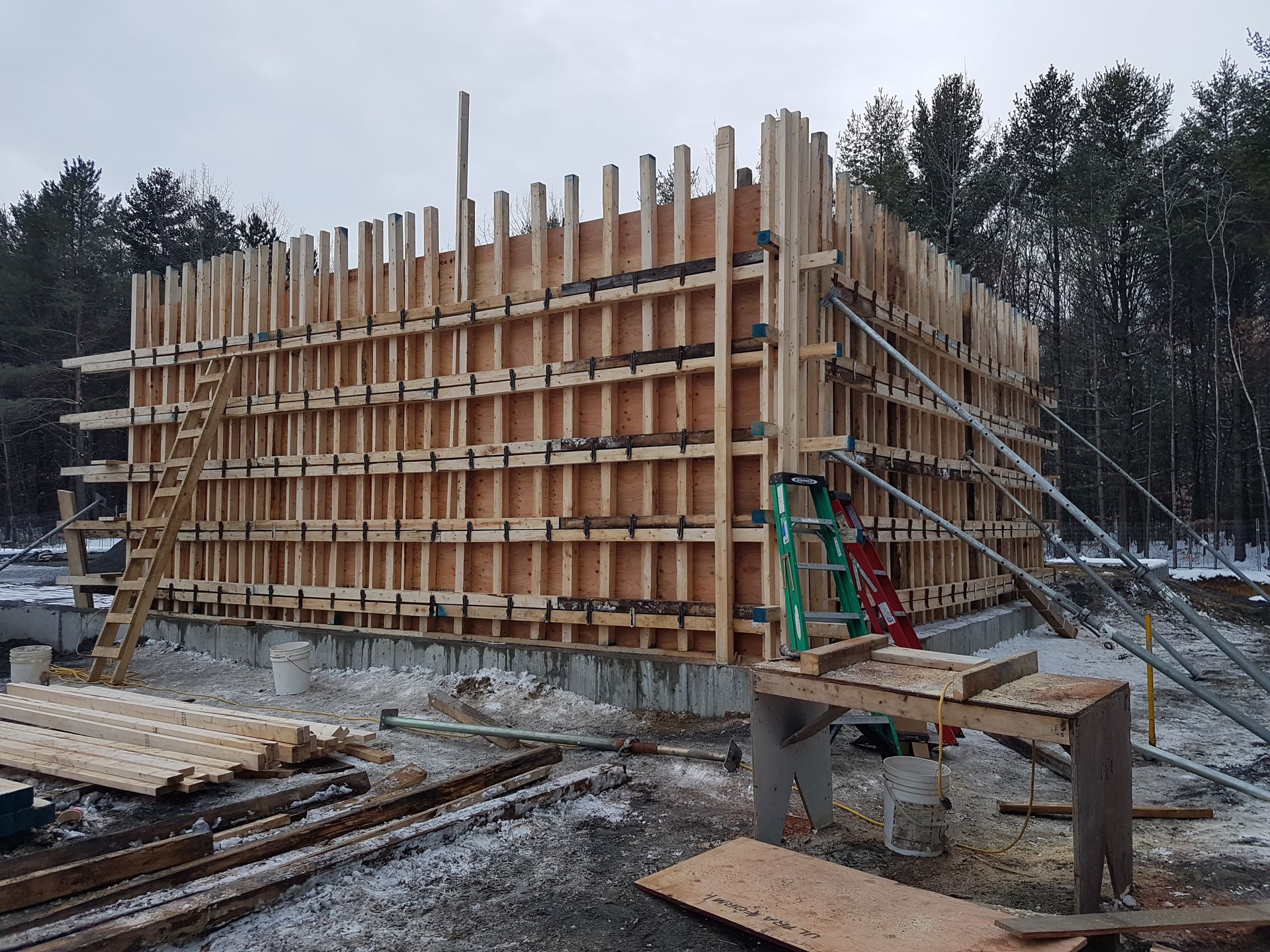 Une grande structure en bois est en cours de construction dans la neige
