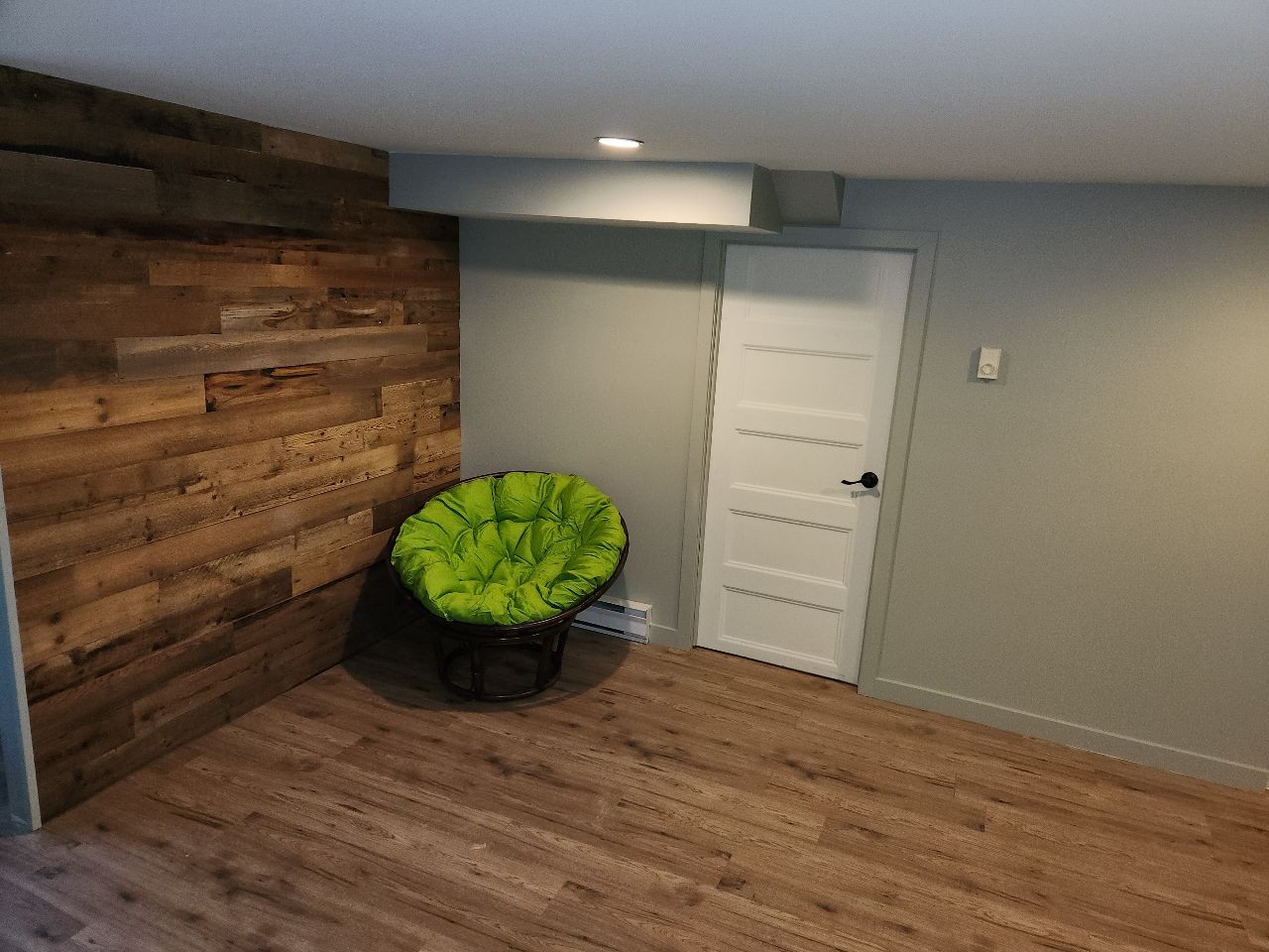 Une pièce avec un mur en bois et une chaise verte.