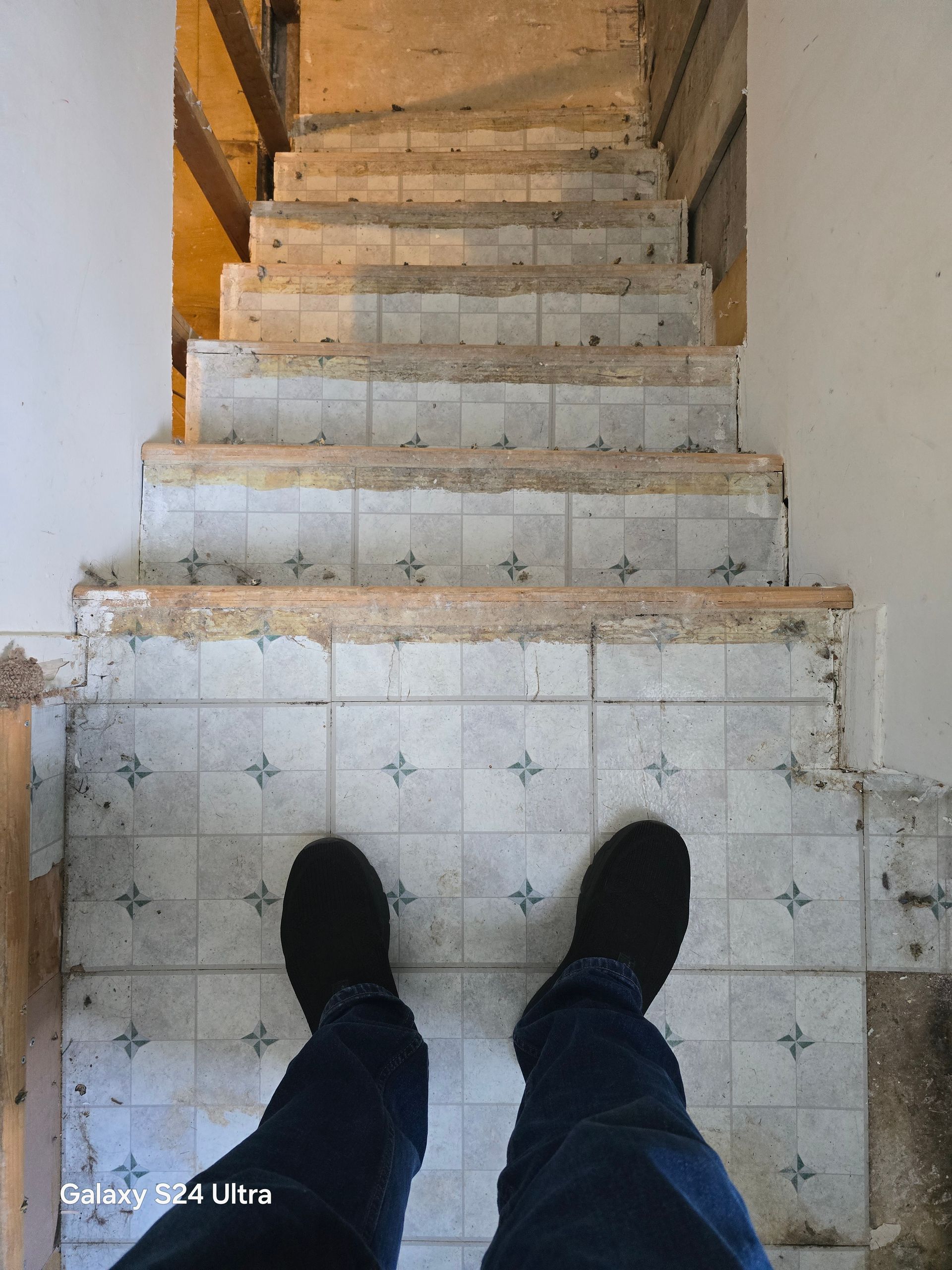 Une personne se tient debout sur un sol carrelé à côté d'un escalier.