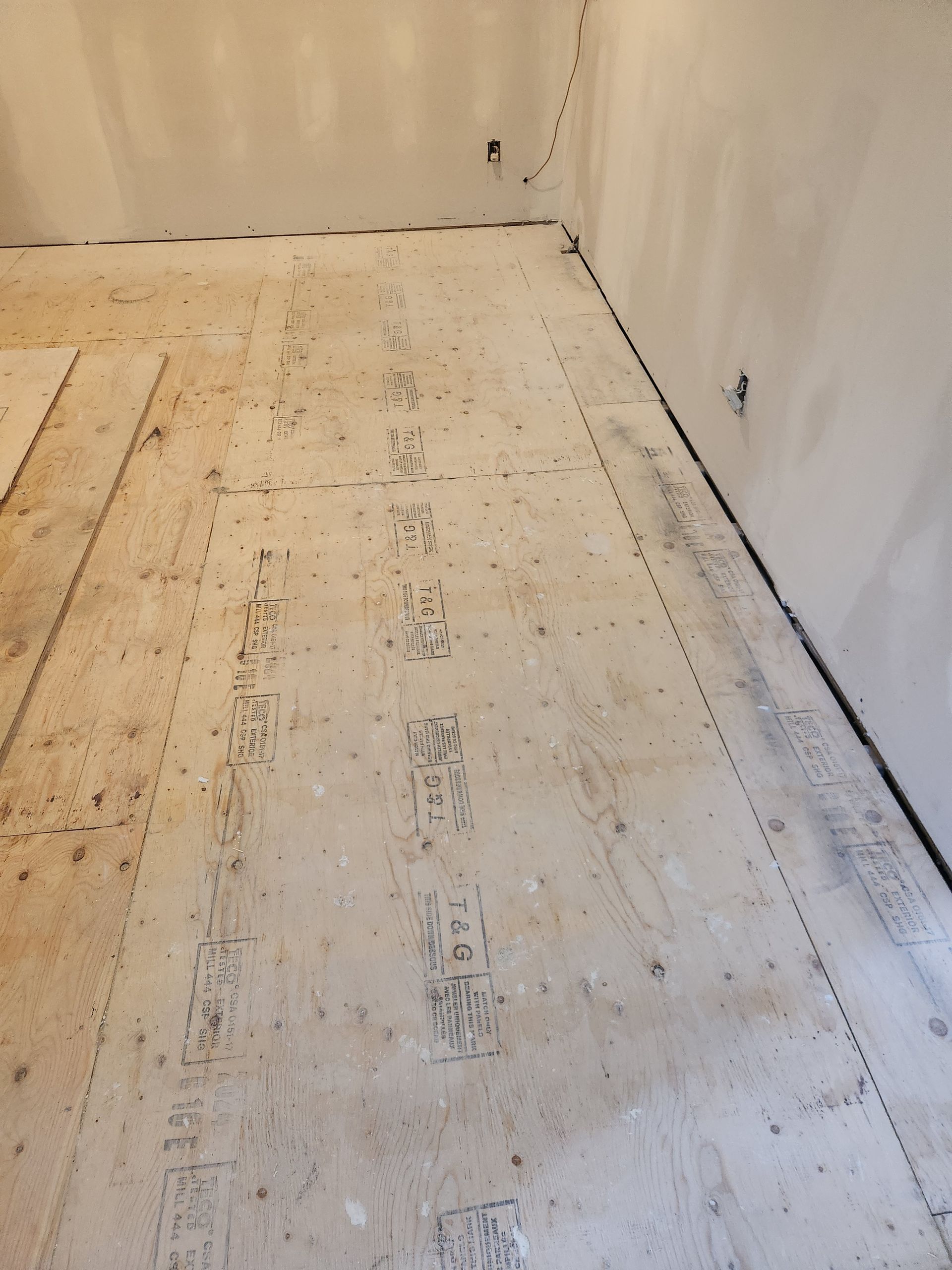 Un coin d'une pièce avec un morceau de contreplaqué sur le sol