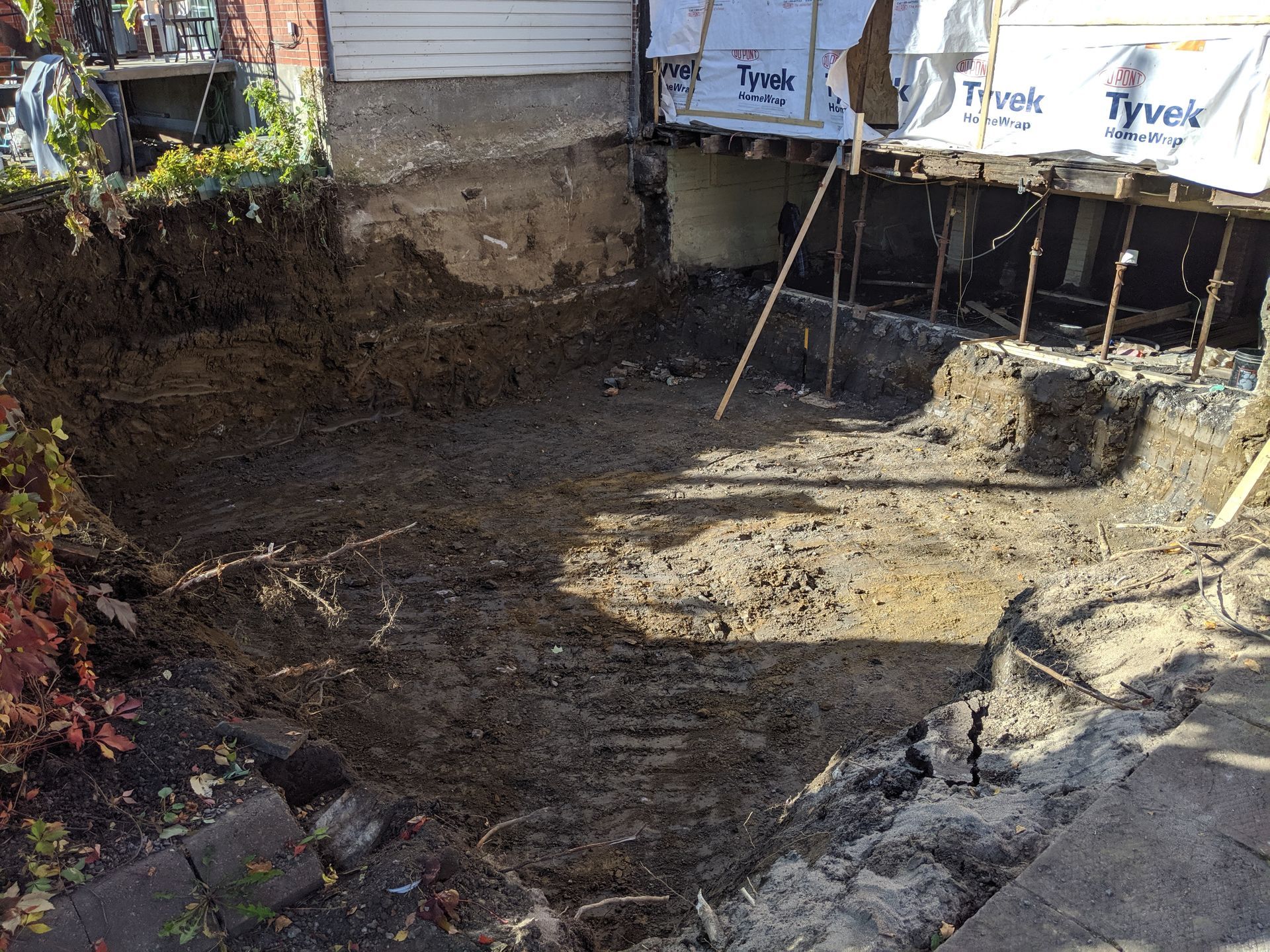 Un grand trou dans le sol à côté d'une maison en construction.