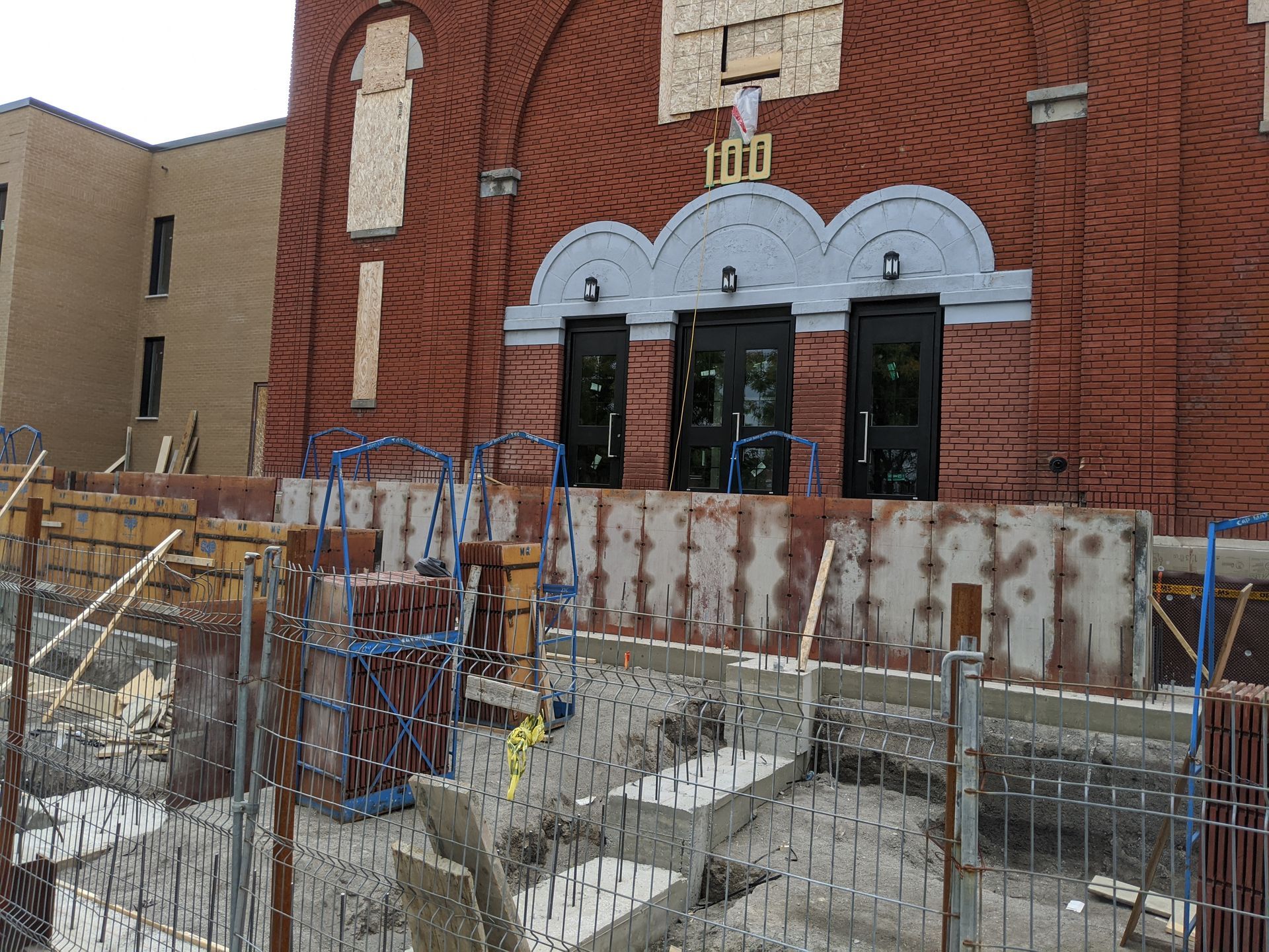 Un bâtiment en briques est en cours de construction avec une clôture autour