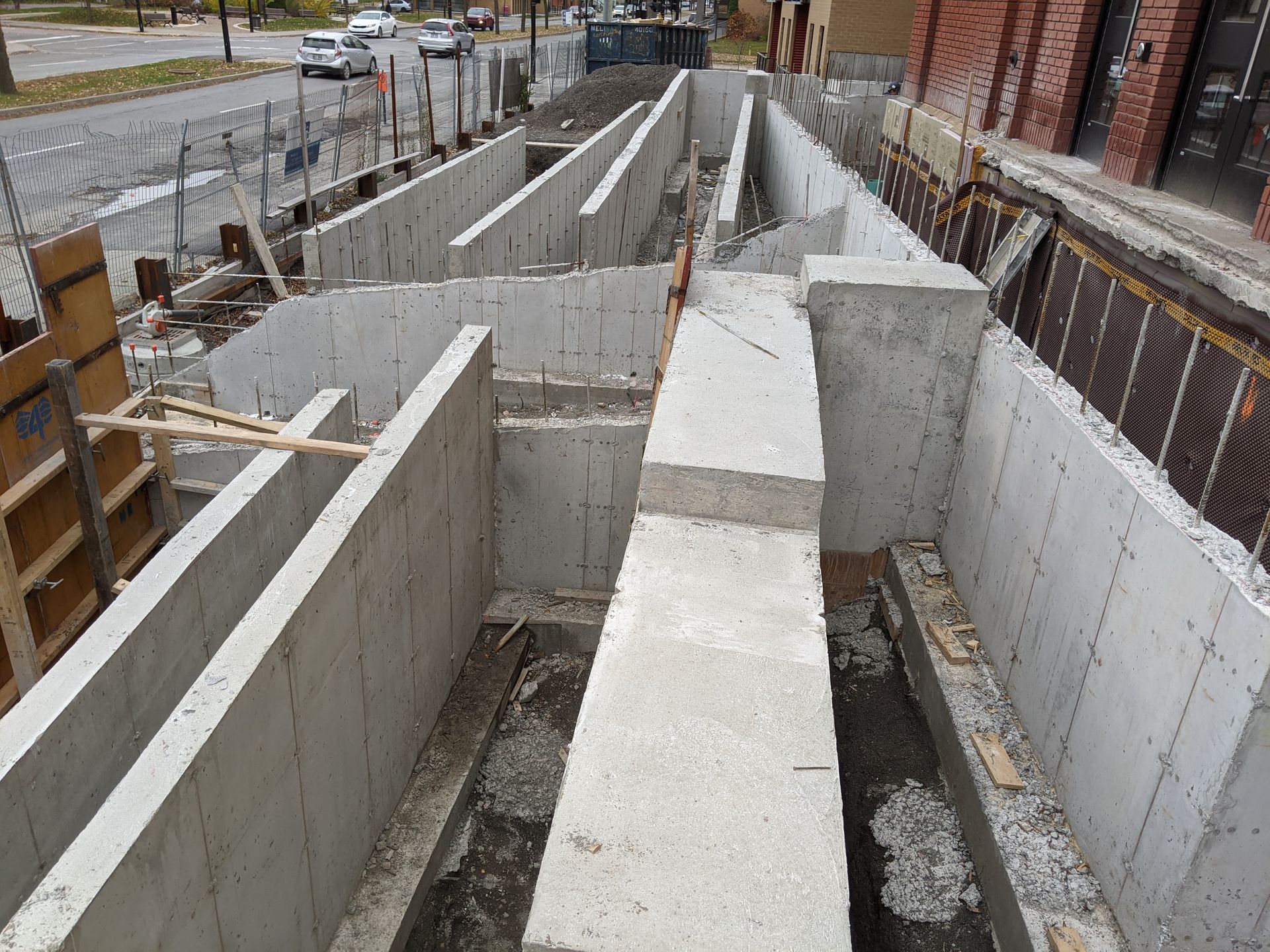 Un chantier de construction avec des murs en béton et un bâtiment en brique en arrière-plan