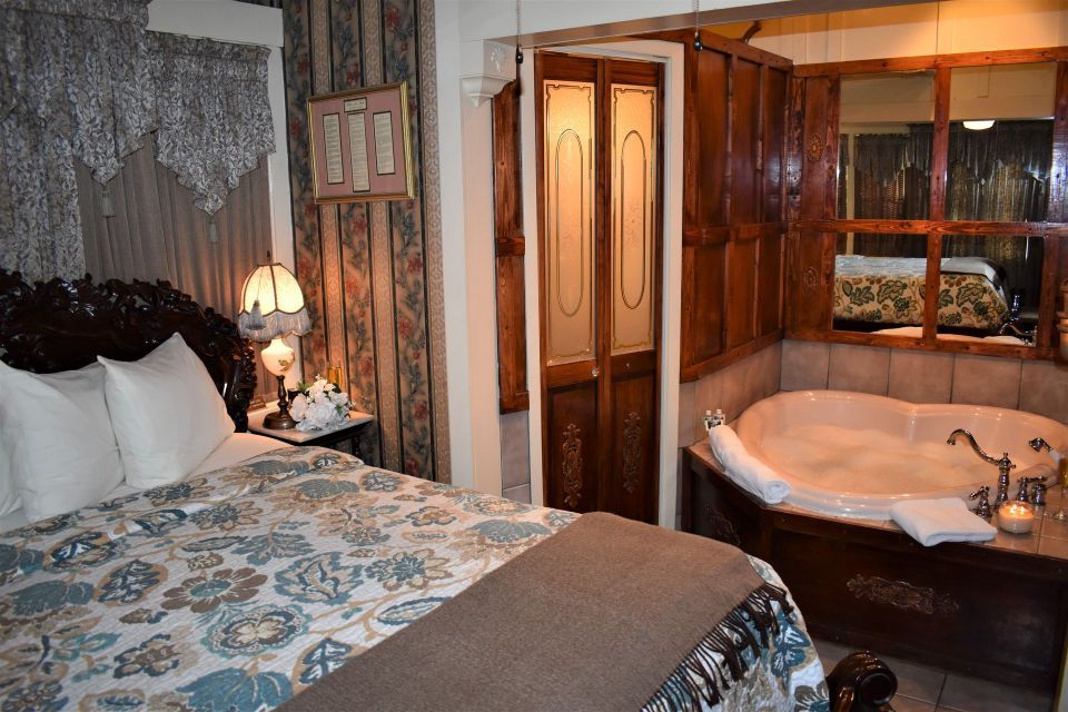 Bedroom with carved dark bed, jacuzzi tub, and a set of frosted glass doors.