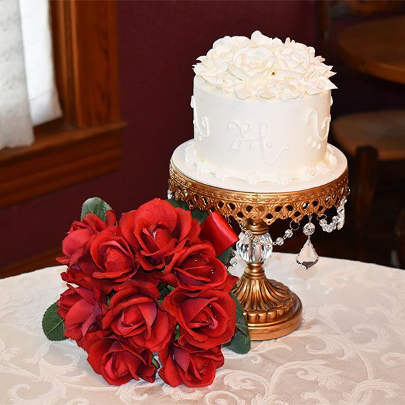 beautiful wedding cake next to red roses