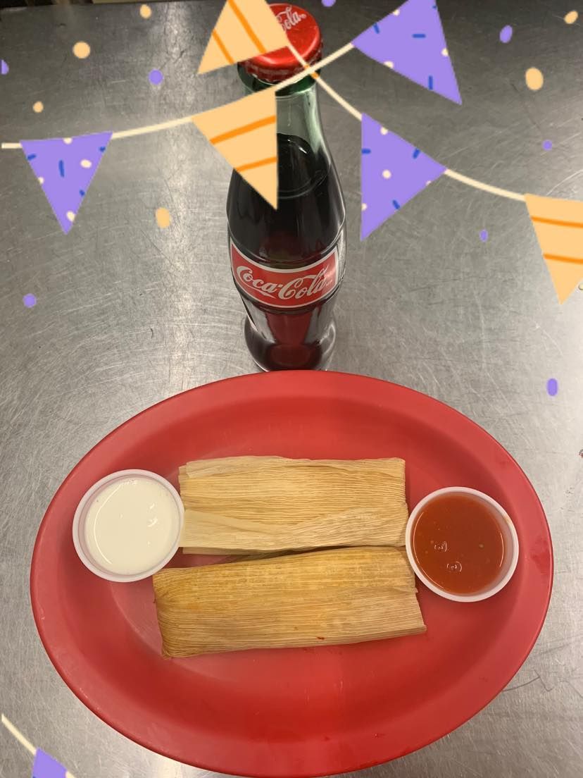 A bottle of coca cola sits next to a plate of food
