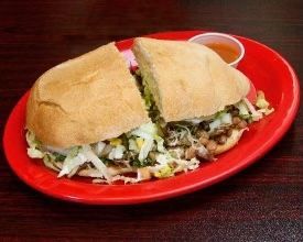 A sandwich on a red plate with a side of sauce.