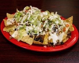 A red plate topped with nachos , lettuce , cheese and sour cream.