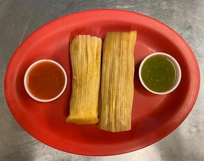 A red plate topped with two tamales and two dipping sauces.