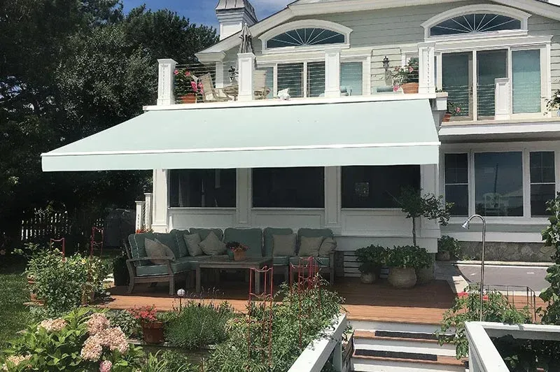 A light blue retractable awning shades a deck with seating.