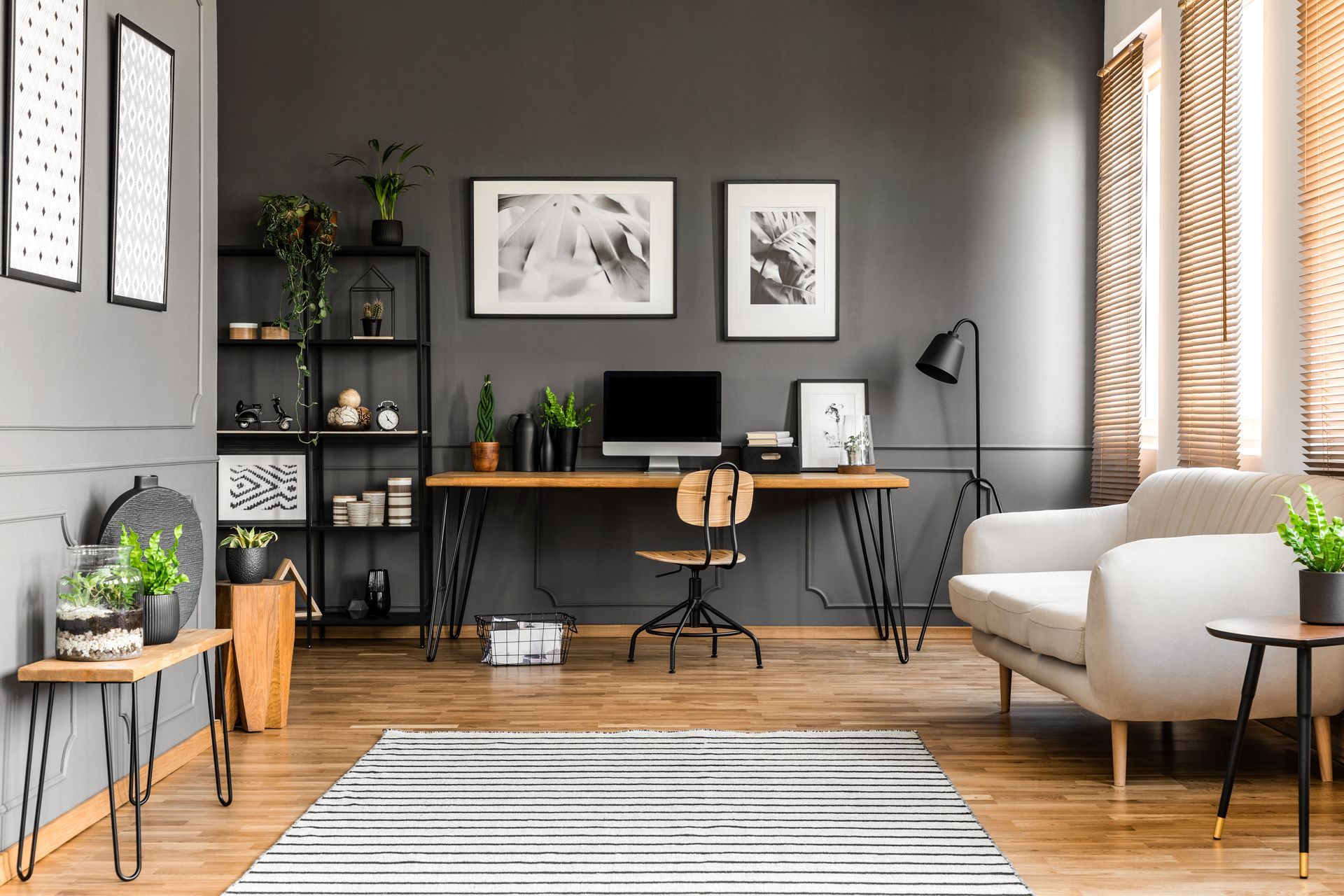 Modern grey office with desk, wall art, and wood window blinds. 
