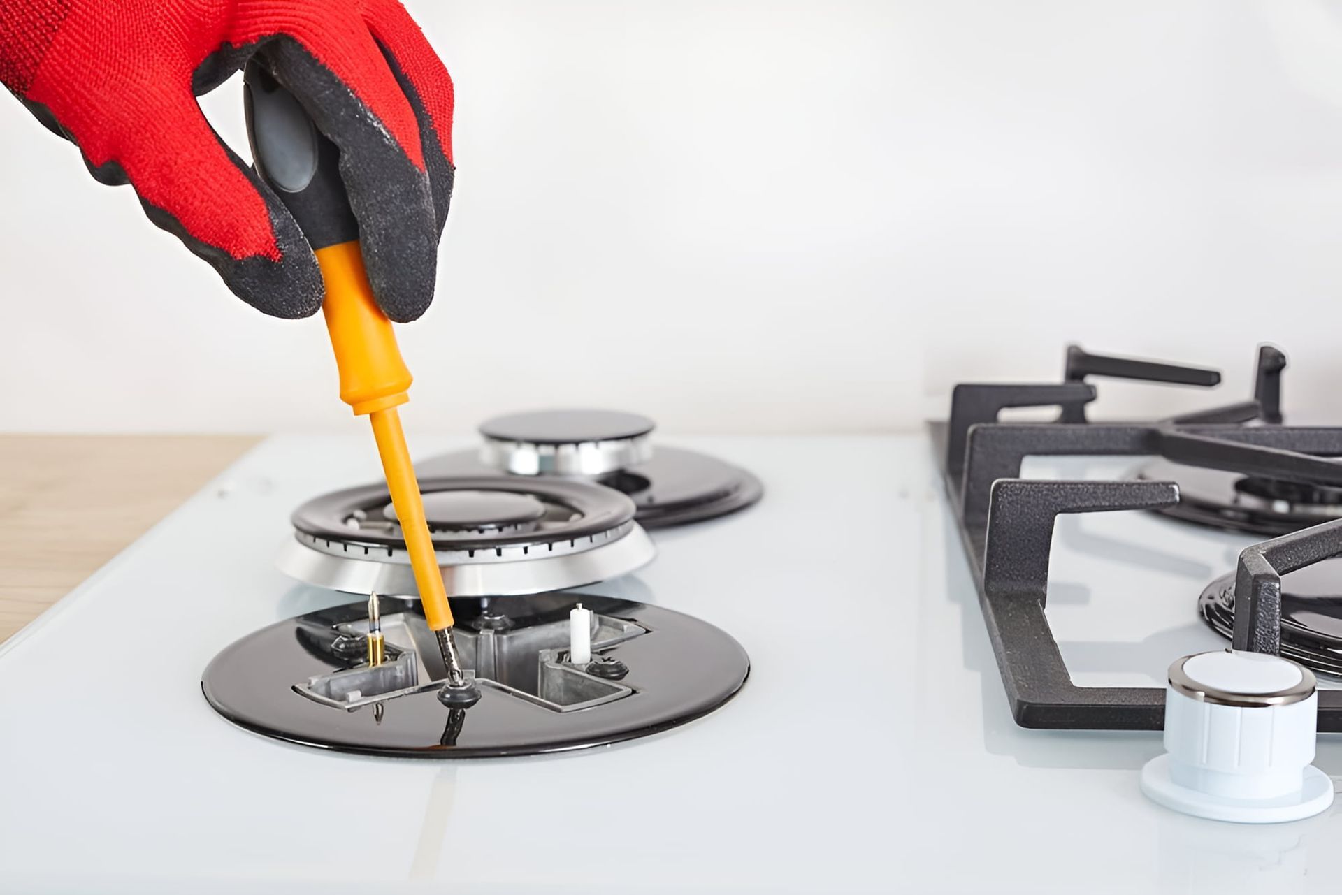 A Person Is Fixing A Gas Stove With A Screwdriver — Tweed Coast Appliance Repairs In Clothiers Creek, NSW