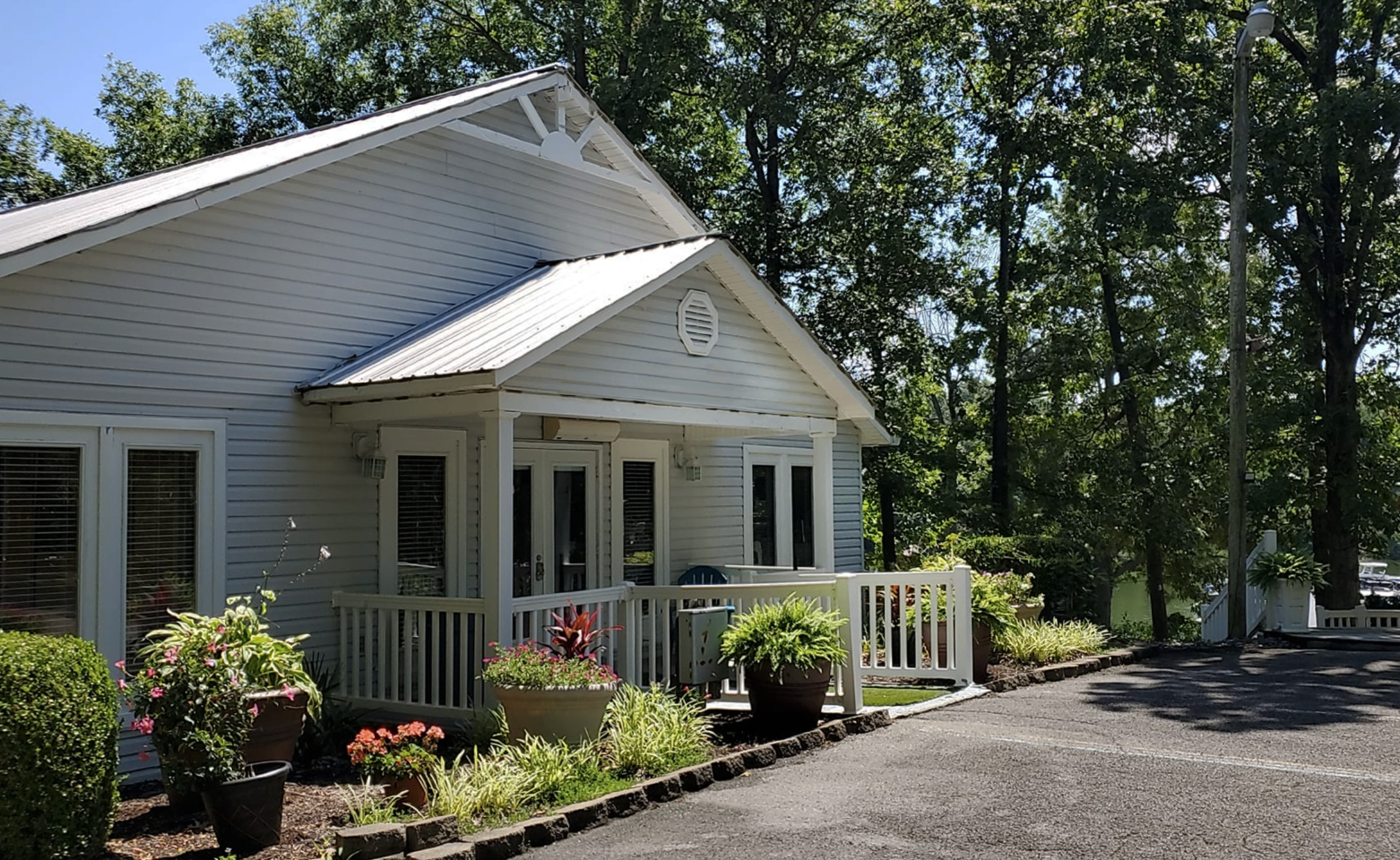 A white house with a porch and trees in the background